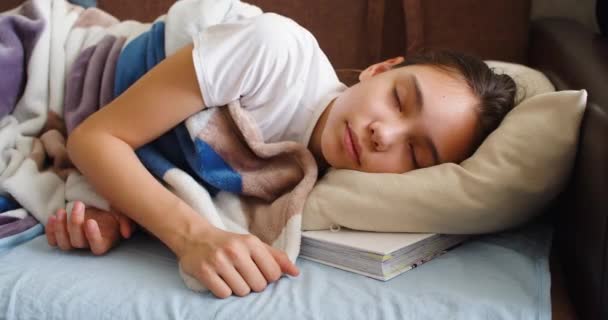Primo piano 4k video di una ragazza sta dormendo con un libro sotto il cuscino - raddrizza la coperta e si sdraia più comodamente. - Filmati, video