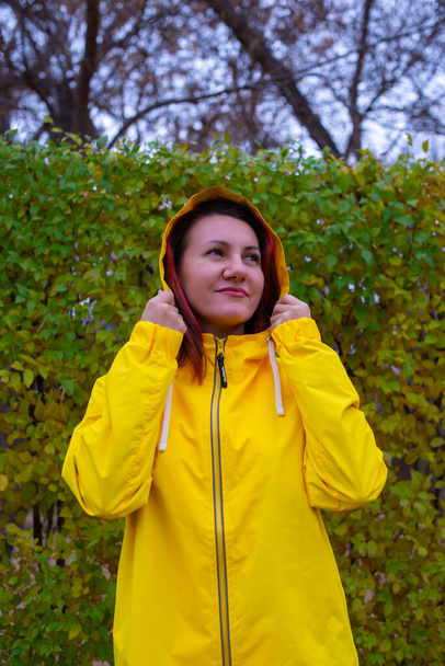 retrato de una niña con una chaqueta amarilla sobre un fondo de árboles. Foto de alta calidad - Foto, Imagen