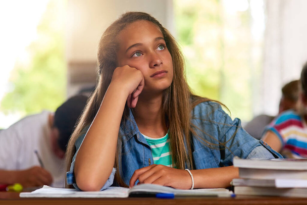 Az álmodozás nem segít átmenni a teszten. egy zavarodott iskoláslány álmodozik az osztályban. - Fotó, kép