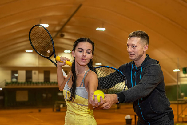 Mutlu kadın ve erkek kapalı sahada oynanacak tenis maçına hazırlanıyor. Tenis oynama konsepti. hobi sporu - Fotoğraf, Görsel