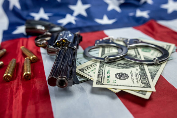 Rahat ja aseet, joissa oli ammuksia ja käsiraudat Amerikan lipussa, takavarikoitiin. rikoksen ja rangaistuksen käsite. rikollisuus - Valokuva, kuva