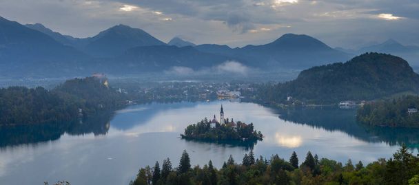Αεροφωτογραφία τοπίου. Πολύχρωμο πρωινό σκηνικό του Προσκυνήματος Εκκλησία της Κοιμήσεως της Θεοτόκου της Μαρίας. Αεροφωτογραφία του φθινοπώρου της λίμνης Bled, Julian Alps, Σλοβενία, Ευρώπη. Ιστορικό ταξιδιωτικής έννοιας. - Φωτογραφία, εικόνα