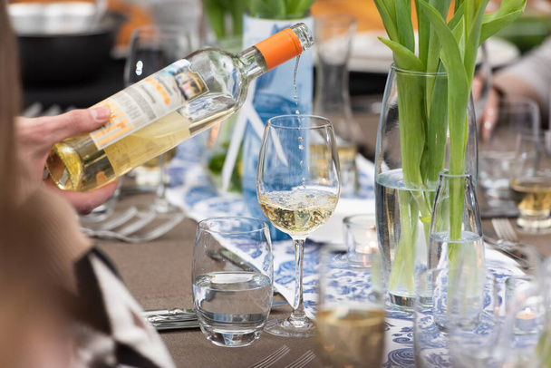Cameriere versare il vino bianco in un bicchiere su un tavolo da ristorante servito - Foto, immagini