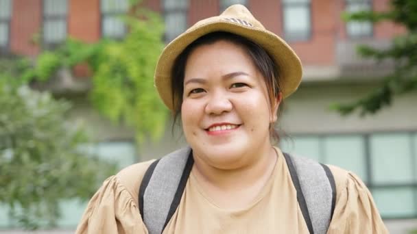 Aasialainen lihava nainen matkustaa yksin Tyytyväinen elämään. Läski nainen katsoo kameraan ja hymyilee. matkustuskäsite - Materiaali, video