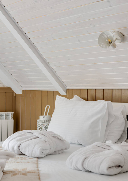 ベッドの上に白いリネンと白いバスローブを備えたホテルの部屋のクローズアップ。高品質の写真 - 写真・画像