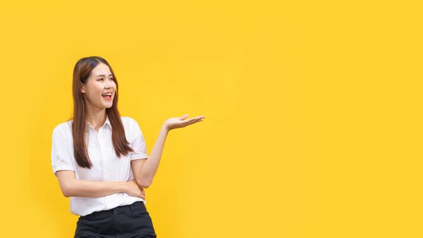 Ženy s úsměvem a ukazující ruku na prezentaci produktu s prázdným prostorem na izolovaném žlutém pozadí. - Fotografie, Obrázek