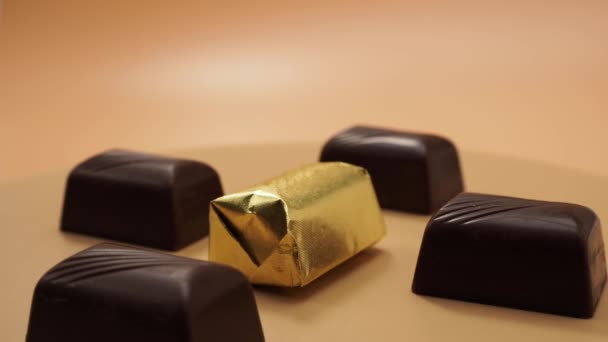Schokoladenbonbons rotieren auf orangefarbenem Hintergrund. Bonbons mit Füllung. - Filmmaterial, Video