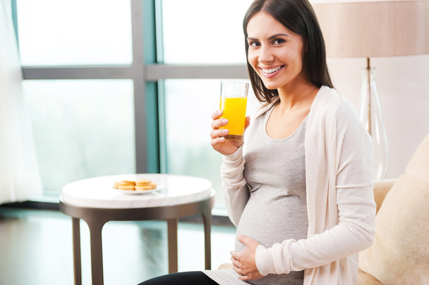 zwangere vrouw bedrijf oranje sap - Foto, afbeelding