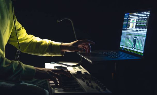 Um homem compositor, produtor, arranjador, compositor, músico mãos arranjando música à noite. - Foto, Imagem