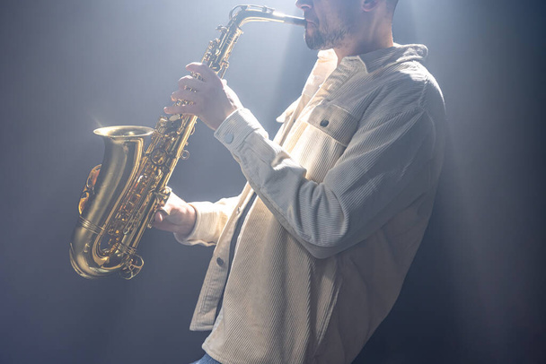 Male musician on stage plays the saxophone dark with smoke. - Photo, Image