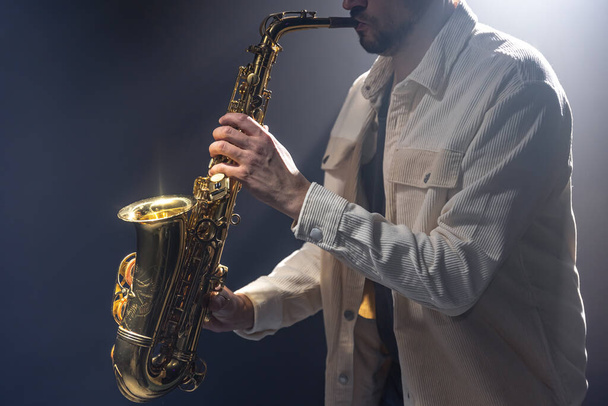 Músico masculino no palco toca saxofone escuro com fumaça, espaço de cópia. - Foto, Imagem
