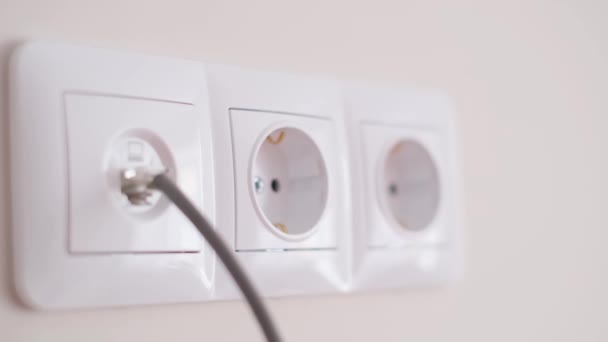 Connecting the electrical appliance to the outlet 100-127 volts 60 hertz. Close-up of a womans hand inserting a plug into an electrical outlet - Video
