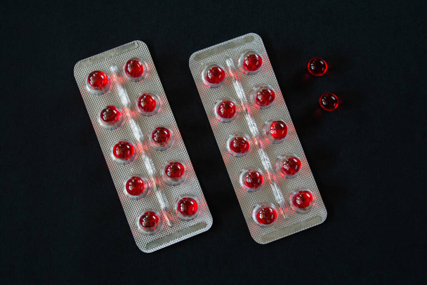 Kulaté červené průsvitné pilulky v blistrech balení na černém pozadí - Fotografie, Obrázek
