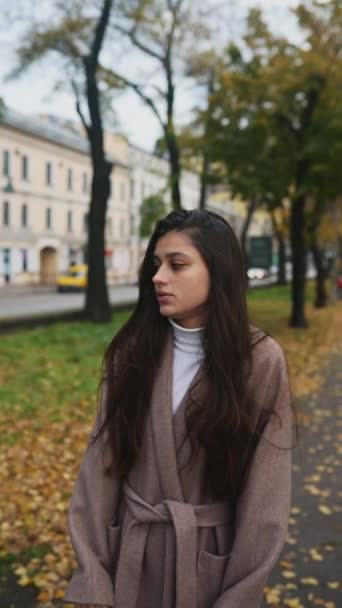Una joven con abrigo de otoño trata de mantener el calor en la calle - Imágenes, Vídeo