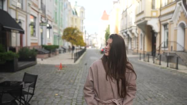Eine junge Frau im Herbstmantel geht durch die Stadt - Filmmaterial, Video