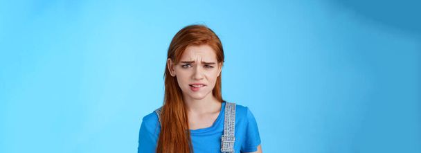 Uneasy upset redhead girl feel uncomfortable, stare frustrated, biting lip frowning, pull sad face upset, apologizing friend, express pity dilsike, stare doubtful uncertain, make bad choice. - Photo, Image
