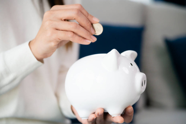 Asian woman putting coin in piggy bank. Save money and investment concept - Photo, Image