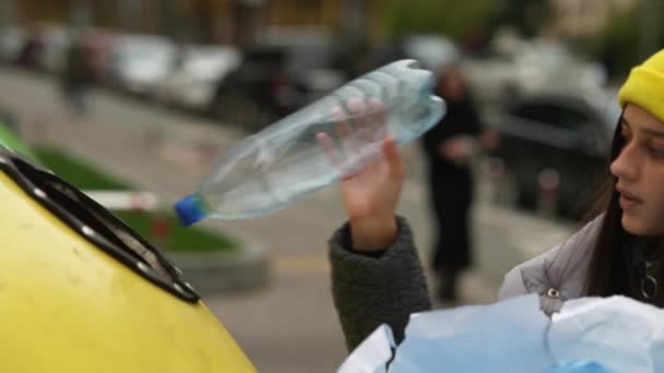 Mujer arrojando basura al punto de reciclaje al aire libre - Imágenes, Vídeo
