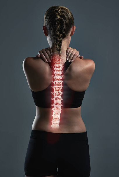 Your body will give you the signals you need. Rearview shot of a sporty young woman holding her back in pain - Photo, Image
