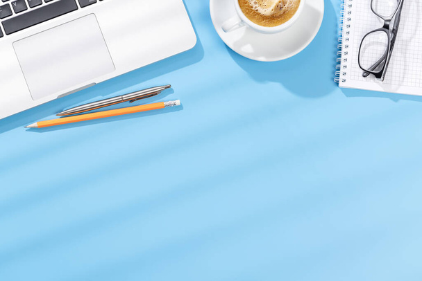 Pracovní stůl s notebookem, kancelářskými potřebami a kávou. Byt ležel pracovní prostor se slunečním světlem a kopírovacím prostorem - Fotografie, Obrázek