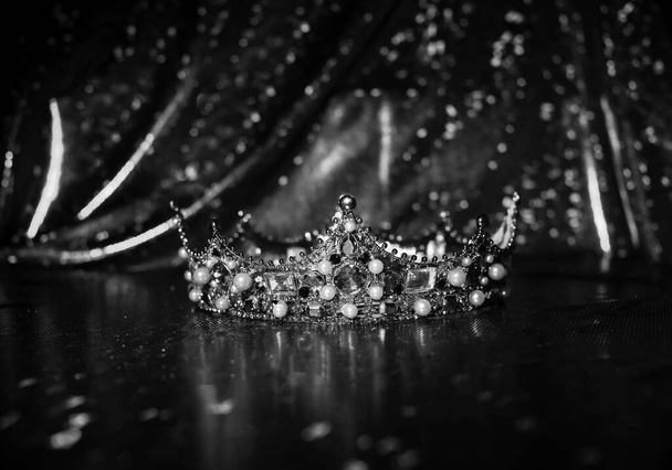 Royal crown with precious gems on red luxury sparkle fabric background. Black and white. - Photo, Image