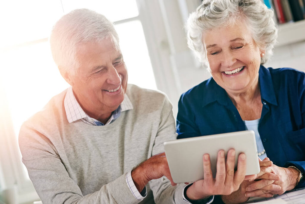 Entdecken Sie alle Tricks der Technologie. ein älteres Paar, das zu Hause gemeinsam ein digitales Tablet benutzt - Foto, Bild