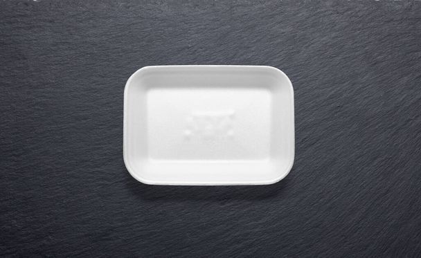 Δίσκος από λευκό φελιζόλ σε μαύρο πλάκα από πάνω - Φωτογραφία, εικόνα
