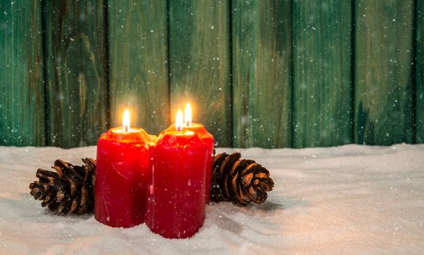 Adviento luz de las velas rojas en el tema de la víspera de Navidad nevada con madera verde. - Foto, imagen