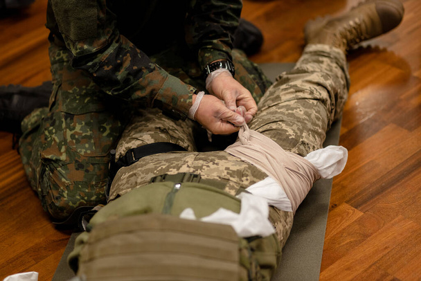  Training dressing of the wounded leg of a Ukrainian fighter, close-up. View from above. High quality photo - Photo, Image