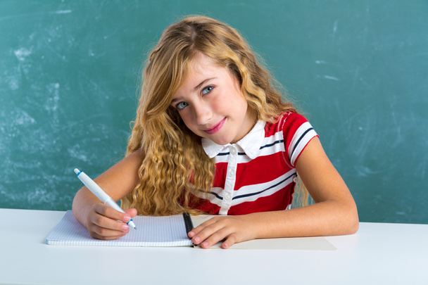 Blond student girl writing notebook at class desk - Photo, image