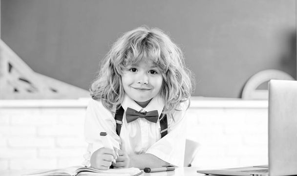 χαρούμενο παιδί με παπιγιόν σπουδάζει στην τάξη του σχολείου στον μαυροπίνακα, σχολείο. - Φωτογραφία, εικόνα