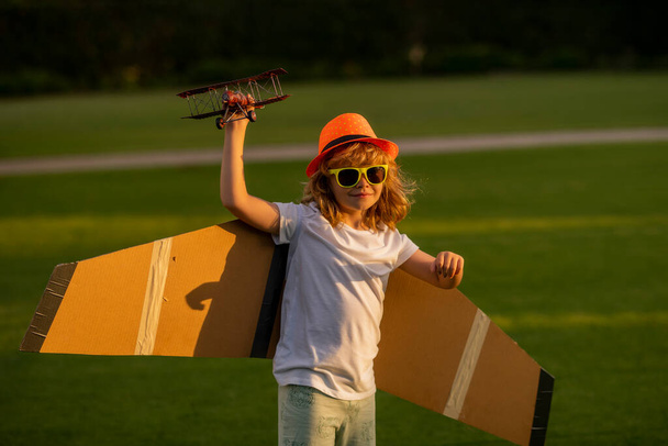 飛行機の翼で遊ぶ子供。田舎の夏の子供たち。子供の頃の思い出、夢の想像力の概念。屋外で遊ぶアクティブな子供 - 写真・画像