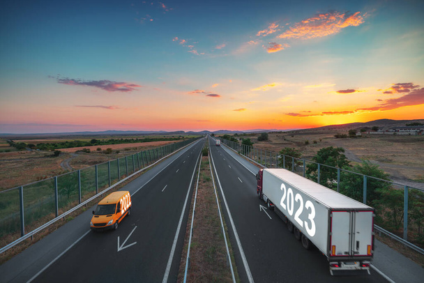 Οδηγώντας σε ανοιχτό δρόμο στο όμορφο ηλιοβασίλεμα προς το επόμενο νέο έτος 2023. Λογιστική βιομηχανία και μεταφορές στην εθνική οδό. - Φωτογραφία, εικόνα