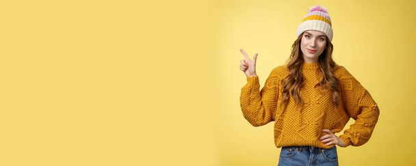 Confident good-looking young female friend telling you buy product immidietely pointing upper left corner smiling hold hand waist self-assured, employee help client pick best merch, yellow background. - Photo, Image