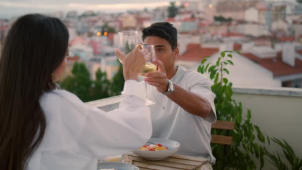 Famille souriante testant champagne au balcon gros plan. Homme et femme joyeux buvant du vin blanc sur la terrasse vue sur la ville. Bonne paire de verres grillés en train de dîner. Jeune couple célébrant anniversaire - Séquence, vidéo