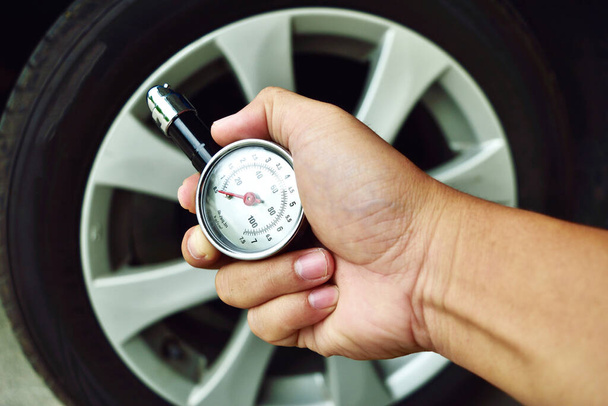 Hand holding pressure gauge for car tyre pressure measurement - Photo, Image