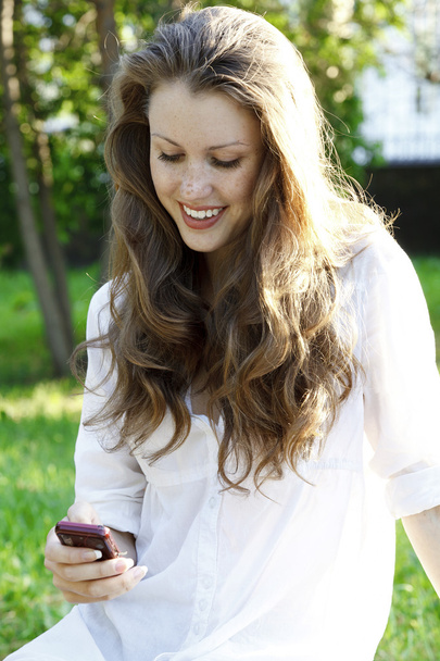 Young woman reads sms on mobile phone - Foto, Imagen