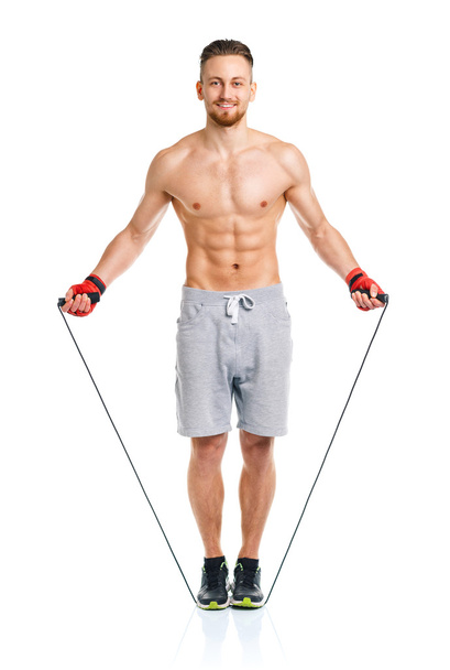 Athletic attractive man jumping on a rope on the white - Фото, зображення