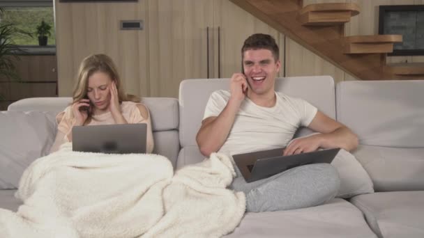 CLOSE UP: Married couple annoying each other at remote work during pandemic time. Young partners being busy using laptops and smartphones while working at home. Twosome working at home in isolation. - Footage, Video