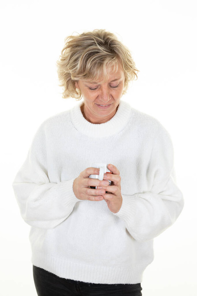 Блондинка середнього віку зимовий светр дивиться чашку кави гарячий напій ізольований білий фон
 - Фото, зображення