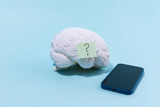 brain health and dementia series, a brain model with a question mark and a cell phone - Valokuva, kuva