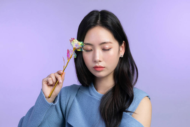 beautiful young Korean Asian woman portrait studio photo in winter skin beauty and cosmetics concept, holding a flower - Foto, afbeelding