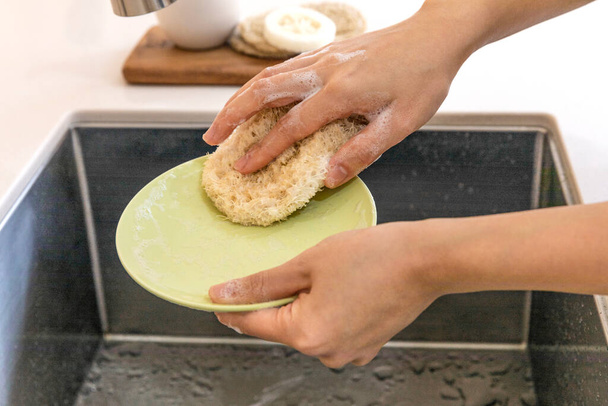 eco friendly habits hand gesture, washing dishes with an eco friendly sponge - Fotoğraf, Görsel