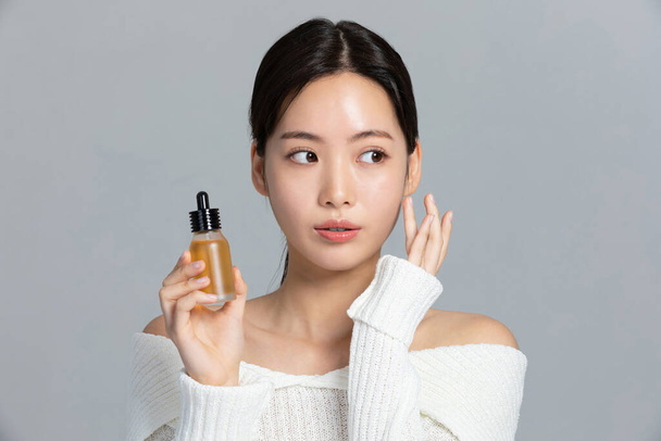 beautiful young Korean Asian woman portrait studio photo in winter skin beauty and cosmetics concept, holding an ample - Foto, Bild