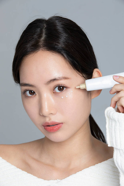 beautiful young Korean Asian woman portrait studio photo in winter skin beauty and cosmetics concept__use eye cream - Foto, Imagem