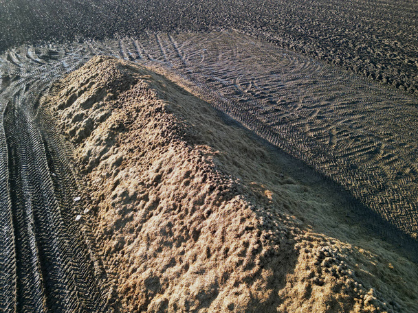 sugar beet dump. on a pile covered with straw as protection against frost.field around pile is strongly compacted and water will not soak in here. heavy tractors, loaders stamped arrow tires, winter - Photo, Image
