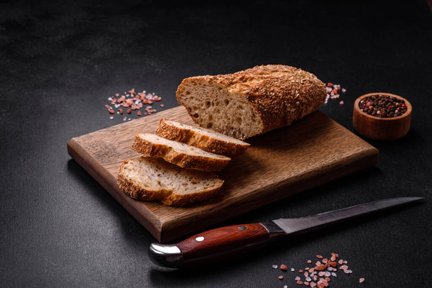 Finom ropogós kenyér szeletekre vágott gabonafélékkel egy fa vágódeszkán - Fotó, kép