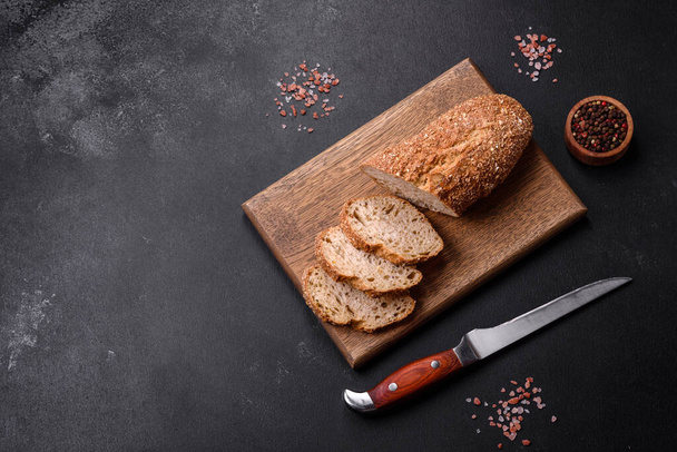 Délicieux pain croustillant avec des céréales coupées en tranches sur une planche à découper en bois - Photo, image