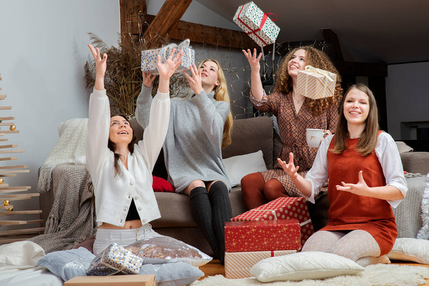 Mosolygó lányok dobálják karácsonyi ajándékaikat a levegőbe - Fotó, kép