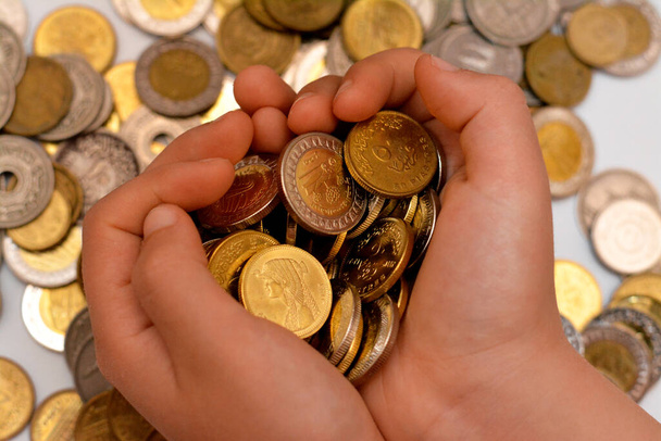 Una pila de monedas en la mano de un niño, pila de monedas de dinero egipcio en poder de un niño pequeño, el concepto de economía futura, la recogida de dinero para la caridad, y el ahorro de dinero - Foto, Imagen
